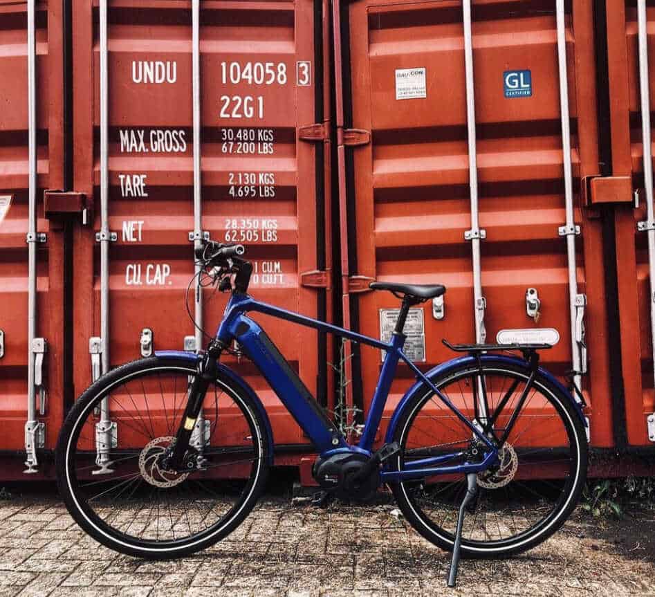 Blaues Fahrrad vor einem roten Container